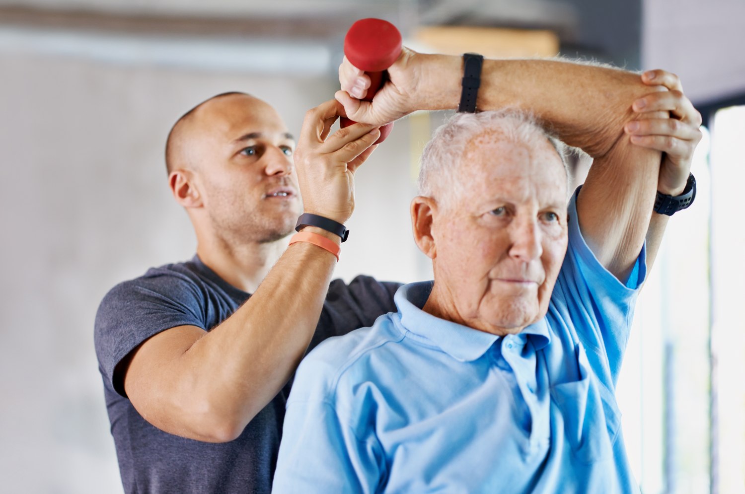 A therapist supporting an older adult during a strengthening exercise
